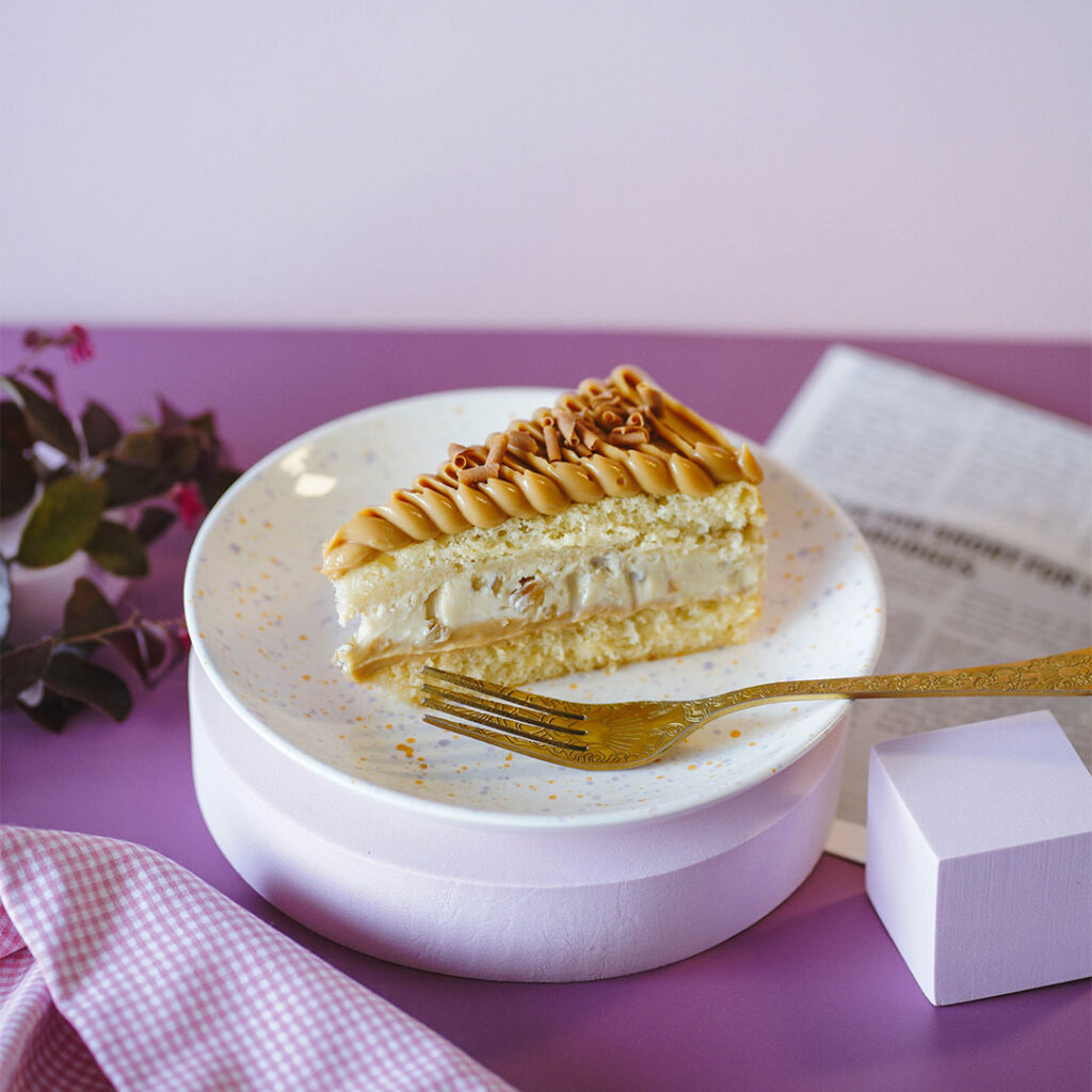 fatia de bolo com recheio de doce de leite e creme de noz, apresentado num prato com garfo, num cenário de luxo